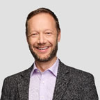 A person with a beard smiling  Description automatically generated