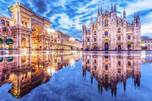 A large building with arches and a large building with a reflection in the water  Description automatically generated